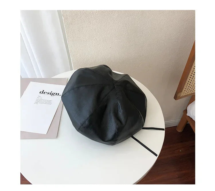 Black faux leather beret with soft, relaxed fit on a white table, modern minimalist style