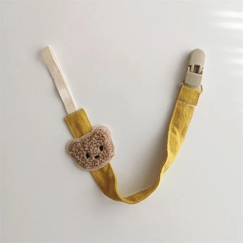 Yellow fabric pacifier clip with beige crochet bear and plastic clasp