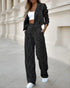 Woman in black and white pinstripe suit with wide-leg pants, cropped blazer, white crop top, and white sneakers
