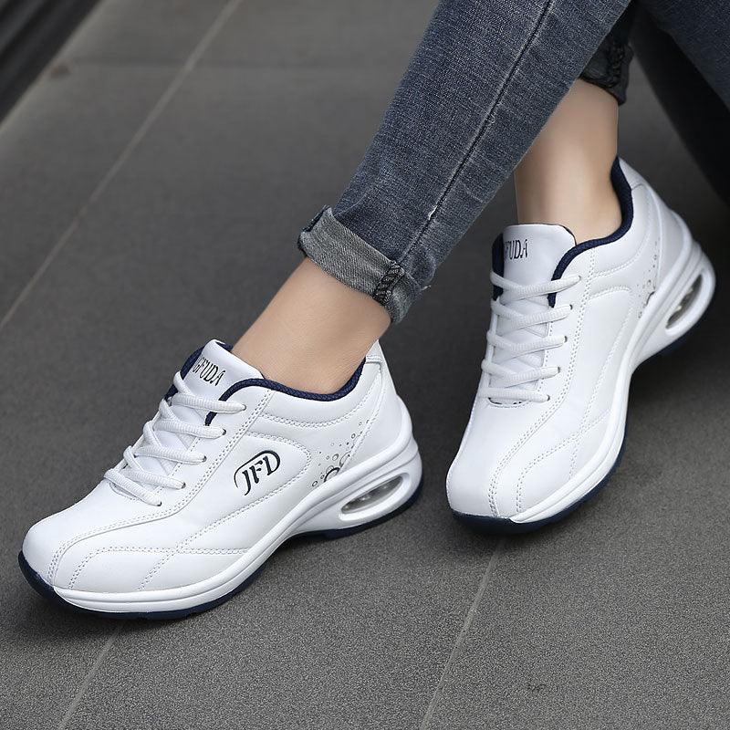 White lace-up sneakers with air-cushioned sole and navy trim, casual fit, worn with skinny jeans