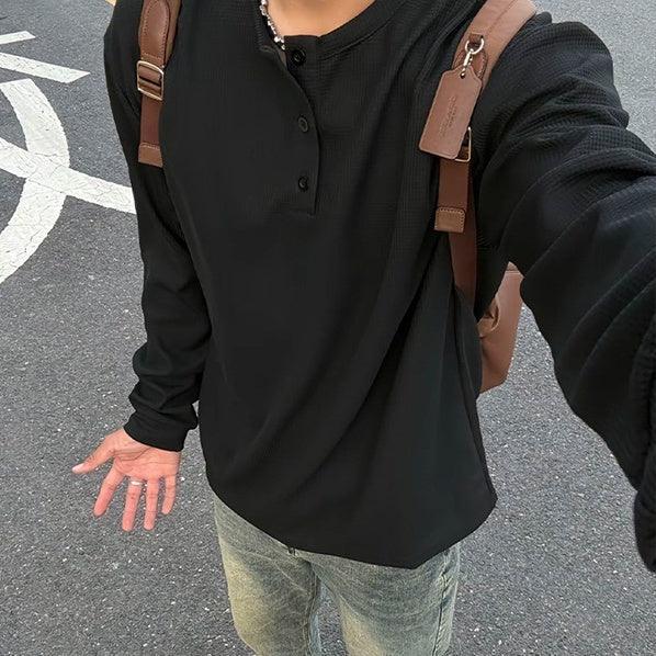 Black long sleeve henley shirt with relaxed fit, paired with faded jeans and brown backpack