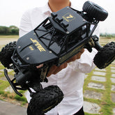 Man in a white button-up shirt holding a black remote-controlled off-road truck.