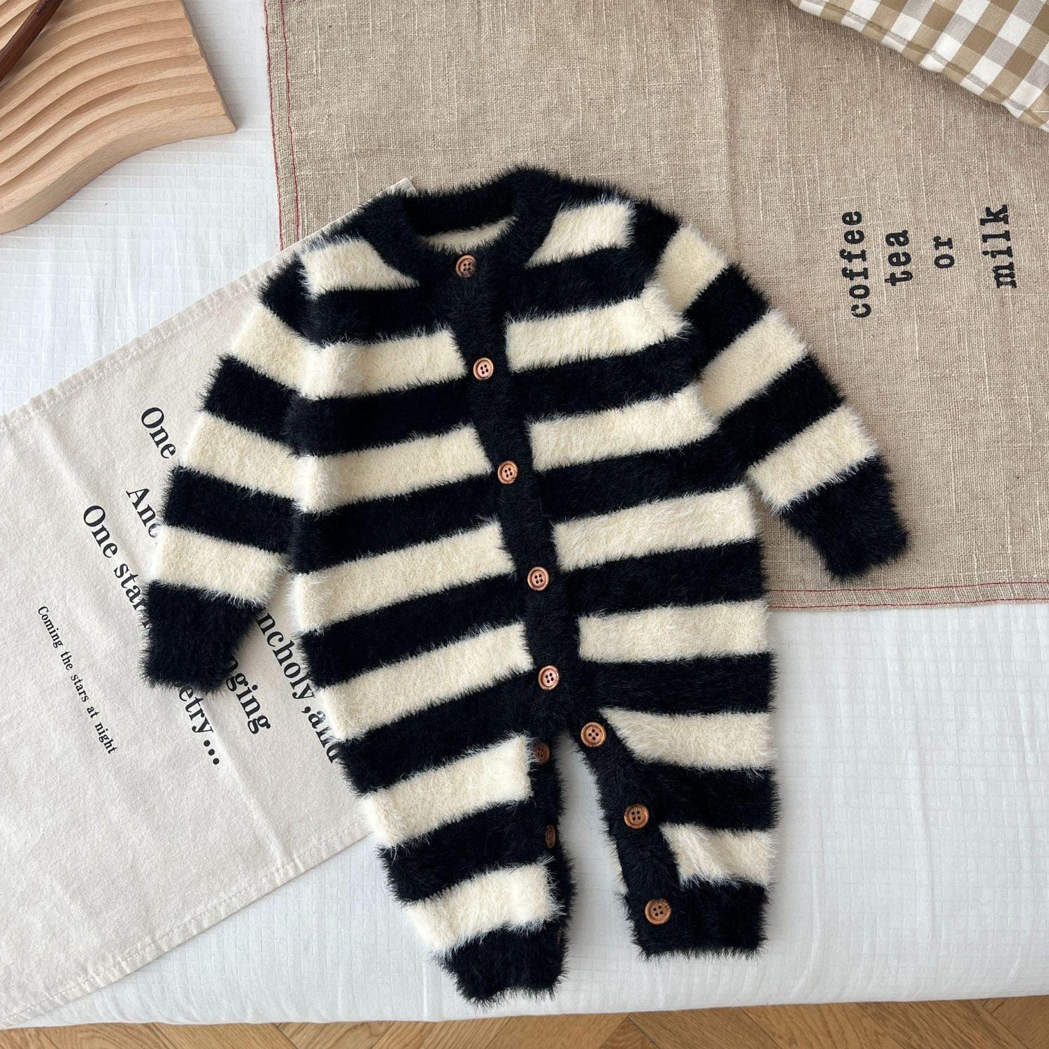 Fuzzy black and white striped baby jumpsuit with wooden buttons, cozy knit material
