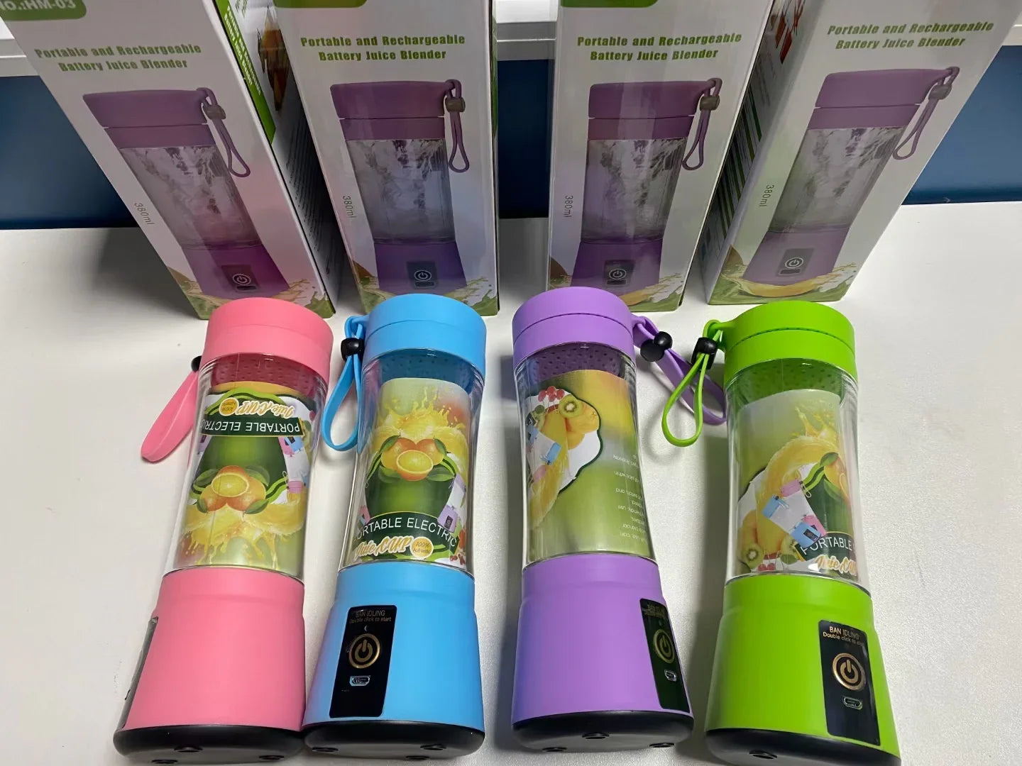 Portable electric blenders in pink, blue, purple, and green with clear plastic bodies and wrist straps.