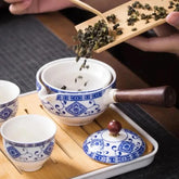 Traditional blue and white ceramic tea set with wooden handle, loose tea being poured