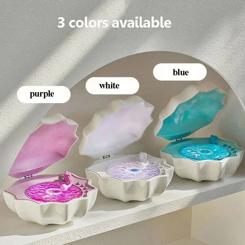 Three clamshell-shaped jewelry boxes in purple, white, and blue with glossy finishes on a shelf.