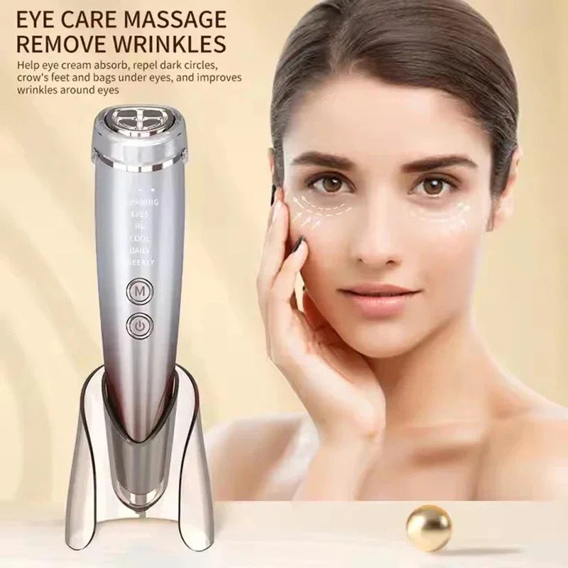 Silver handheld eye massager device with LED display and buttons, beige background, minimal style