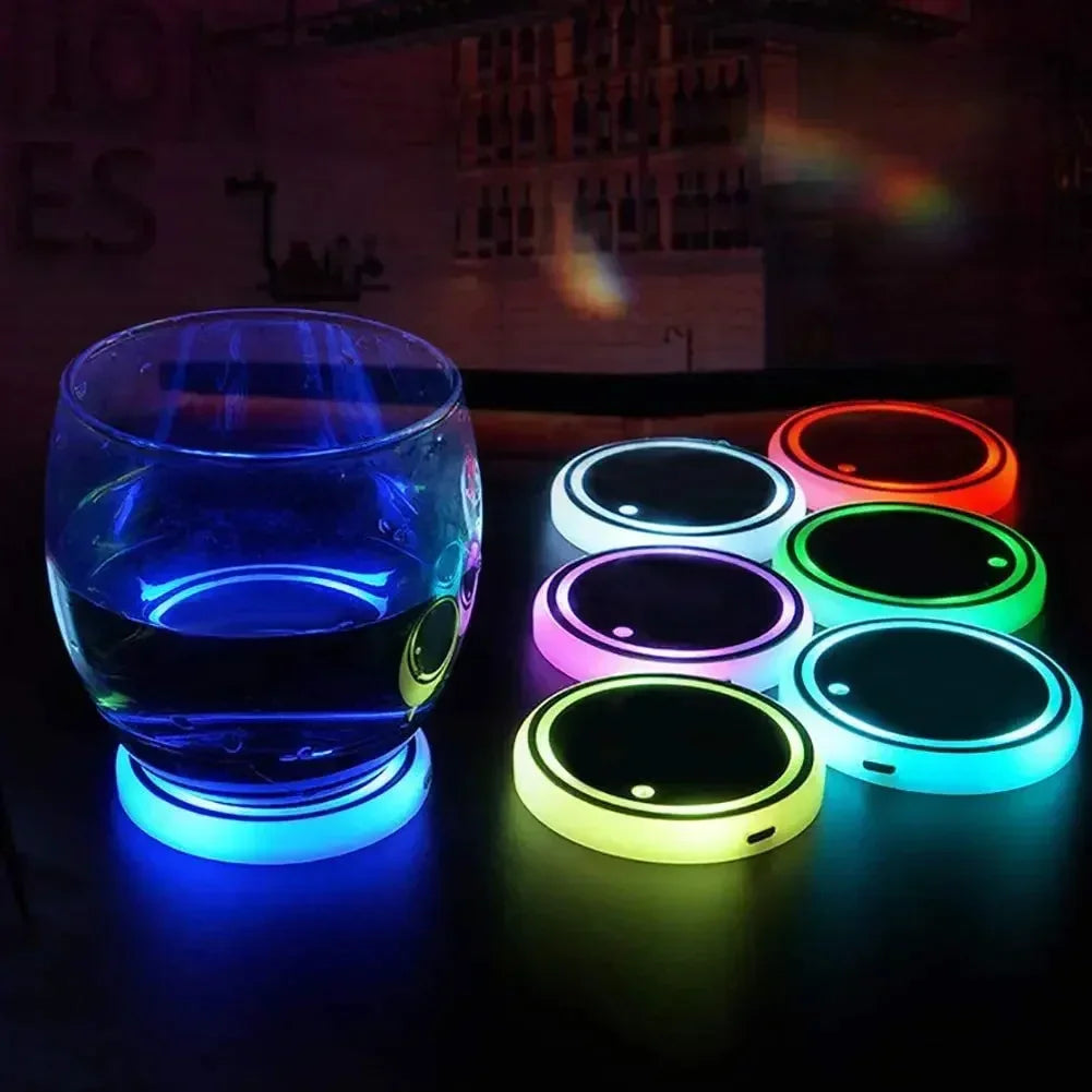 Round glass on blue LED light-up coaster with assorted colorful glowing drink coasters on table