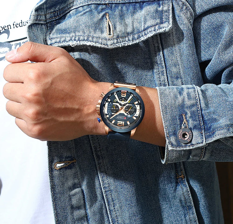 Close-up of a blue and gold watch on wrist, person wearing a light wash denim jacket.