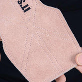 Close-up of a pink suede fabric patch with detailed stitching and part of printed text.