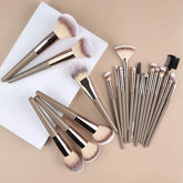 Set of beige and gold makeup brushes with soft bristles, various shapes and sizes, on neutral background