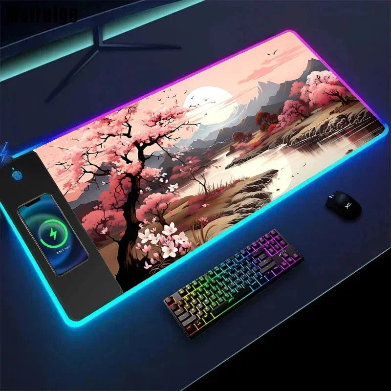 Large RGB LED mouse pad with cherry blossom and mountain landscape design, wireless charging, paired with a rainbow backlit keyboard and mouse.
