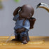 Small ceramic monk figurine in blue robe, pouring water fountain, on wooden surface