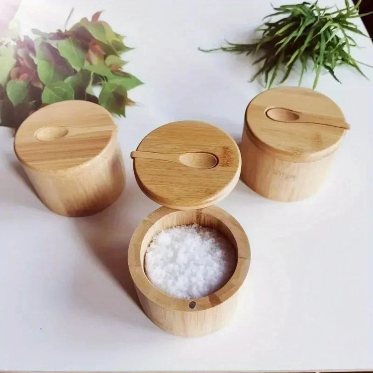 Set of round bamboo spice containers with lids, one open showing salt, on a white table