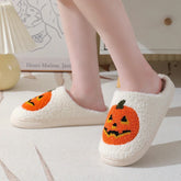 Fuzzy cream slippers with orange jack-o-lantern pumpkin design and cozy closed-toe fit