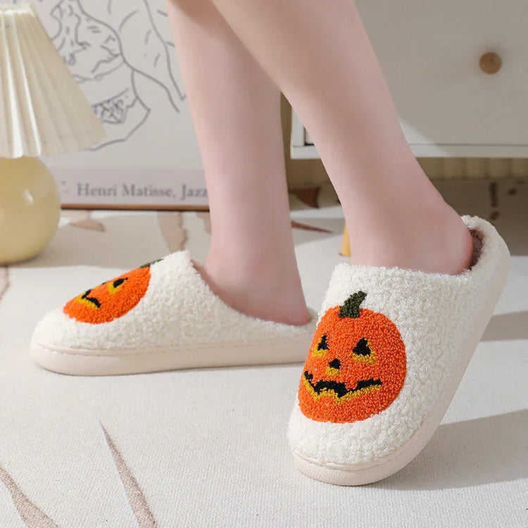 Fuzzy cream slippers with orange jack-o-lantern pumpkin design and cozy closed-toe fit