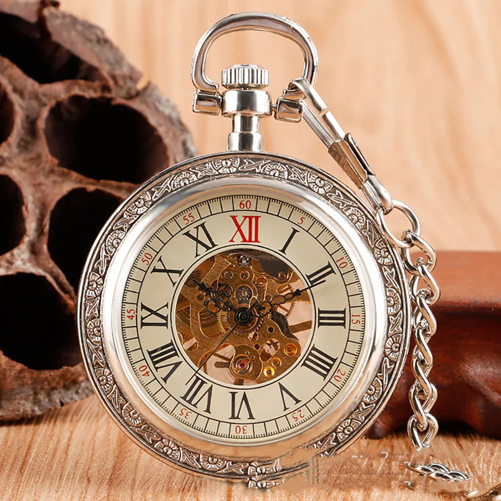 Silver vintage pocket watch with Roman numerals and exposed mechanical gears on wood surface.