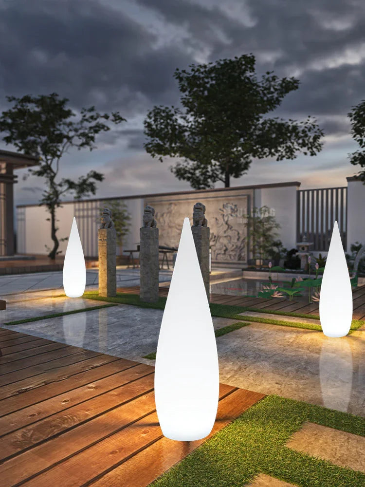Modern outdoor setting with tall cone-shaped white LED lights on wood and grass patio