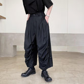Loose-fit black pleated pants in lightweight fabric, cropped length, paired with black shirt and shoes