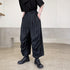 Loose-fit black pleated pants in lightweight fabric, cropped length, paired with black shirt and shoes