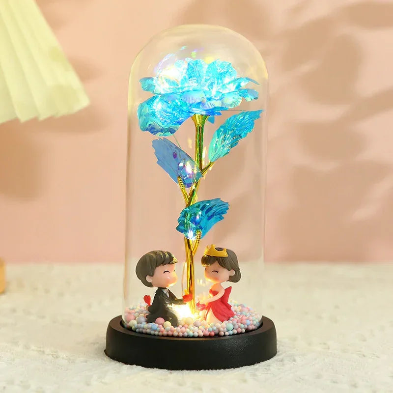 Decorative glass dome with blue rose, gold stem, and two cute figurines on black base