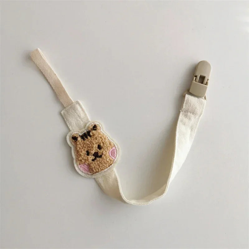 Beige cotton pacifier clip with cute embroidered bear face and plastic clasp