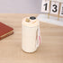 Cream insulated travel mug with digital temperature display and carrying strap on wooden desk