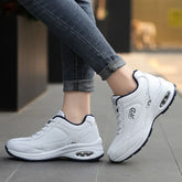 White athletic sneakers with air-cushioned sole, low-top design, worn with rolled jeans.