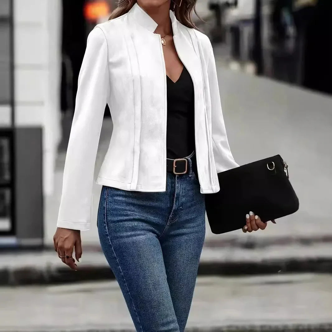 Woman wearing a fitted white blazer, black top, blue jeans, and holding a black clutch
