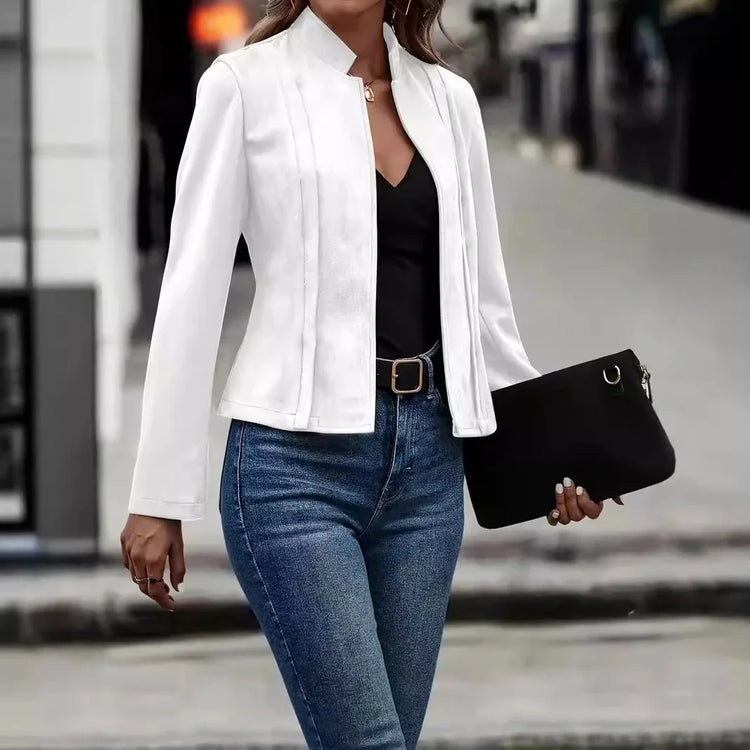Woman wearing a fitted white blazer, black top, blue jeans, and holding a black clutch