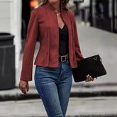 Woman wearing fitted red blazer, black top, and blue skinny jeans with a black clutch