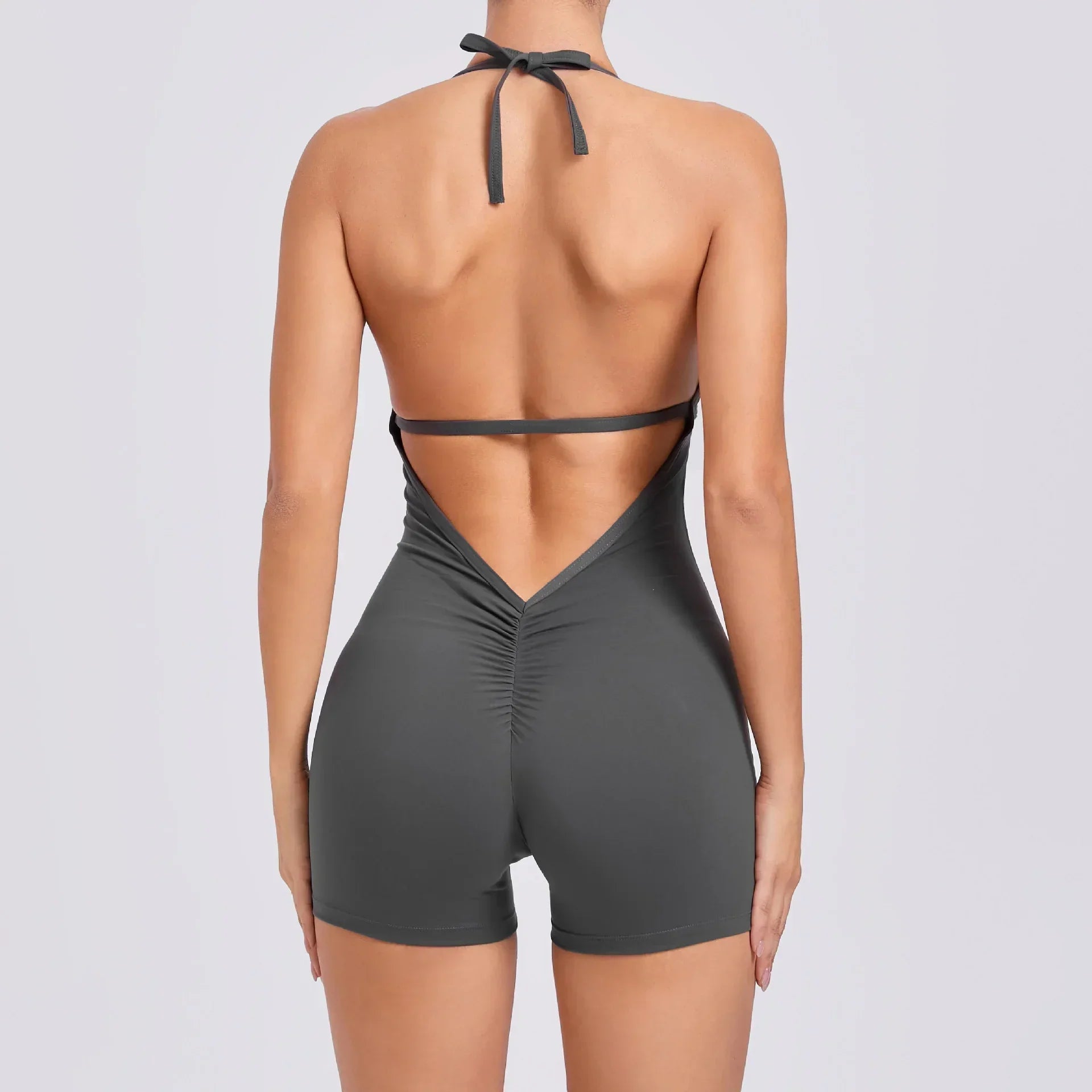 Back view of woman in gray halter neck, backless romper with ruched detailing, slim fit
