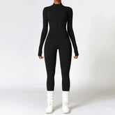 Woman wearing a black fitted long sleeve jumpsuit with front zipper, white socks, and sneakers