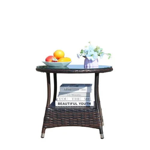 Round wicker side table with a glass top, holding a fruit bowl and a vase of flowers