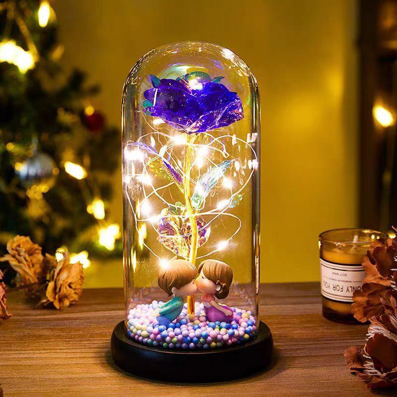 Colorful artificial rose with LED fairy lights in glass dome, cute couple figurines, decorative display.