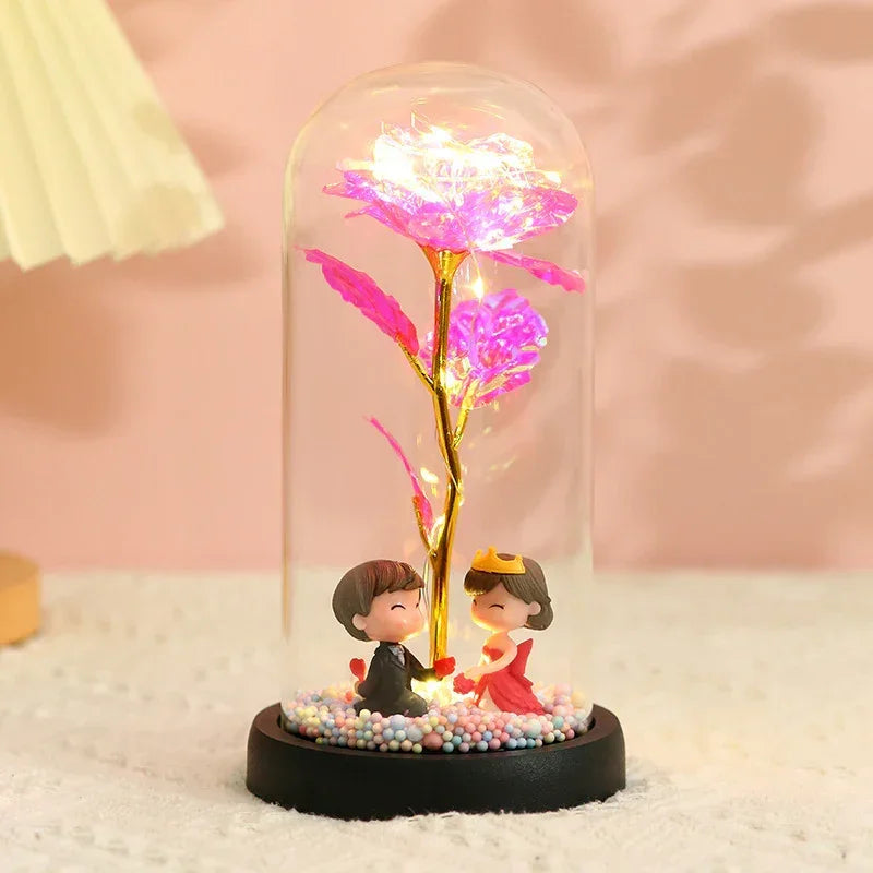 Glass dome with LED rose flower and romantic figurines, decorative pink lighting.