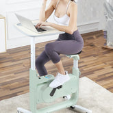 Woman in white sports bra and gray leggings using a laptop on a stationary bike desk