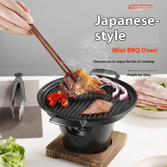 Mini tabletop BBQ grill with steaks, sliced red chili, and onions being cooked, modern indoor setting.