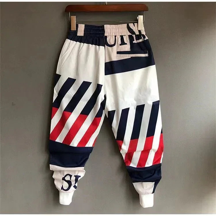 Futuristic streetwear jogger pants with bold navy, red, and white geometric stripes, relaxed fit