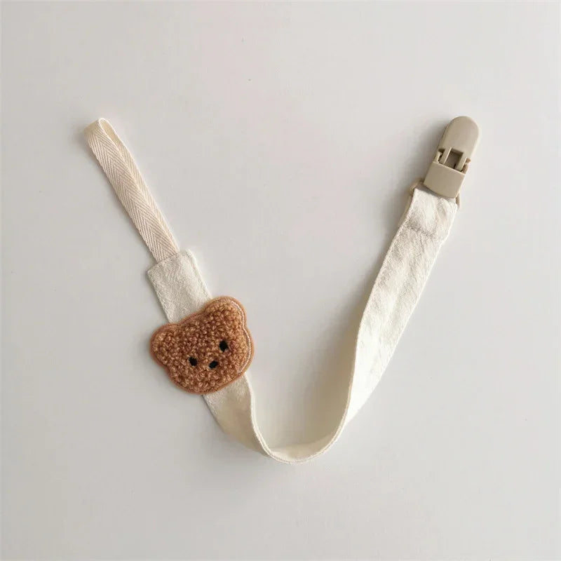 Cream fabric pacifier clip with brown knit bear face and plastic clasp