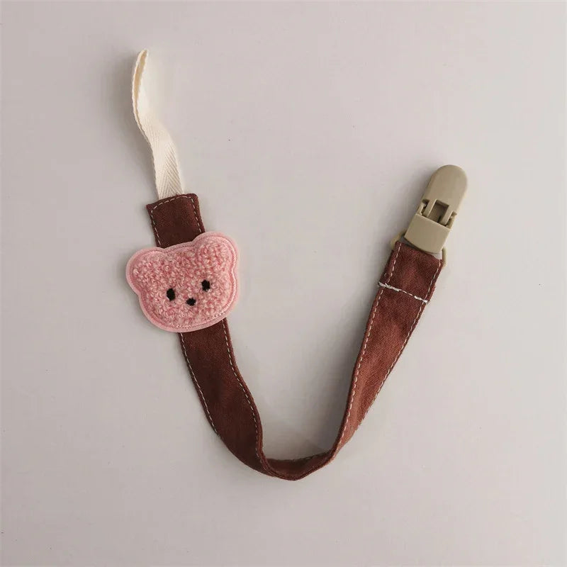 Brown velvet pacifier clip with pink crochet bear design and beige plastic clasp