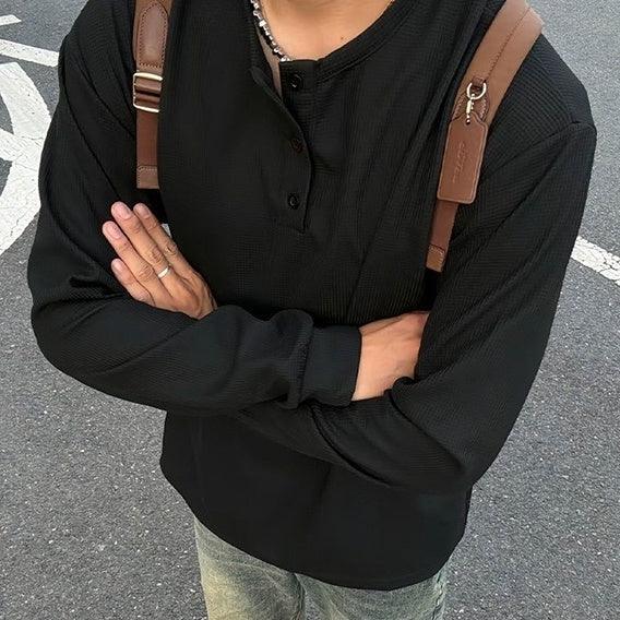 Black long sleeve henley shirt with relaxed fit, paired with brown backpack straps