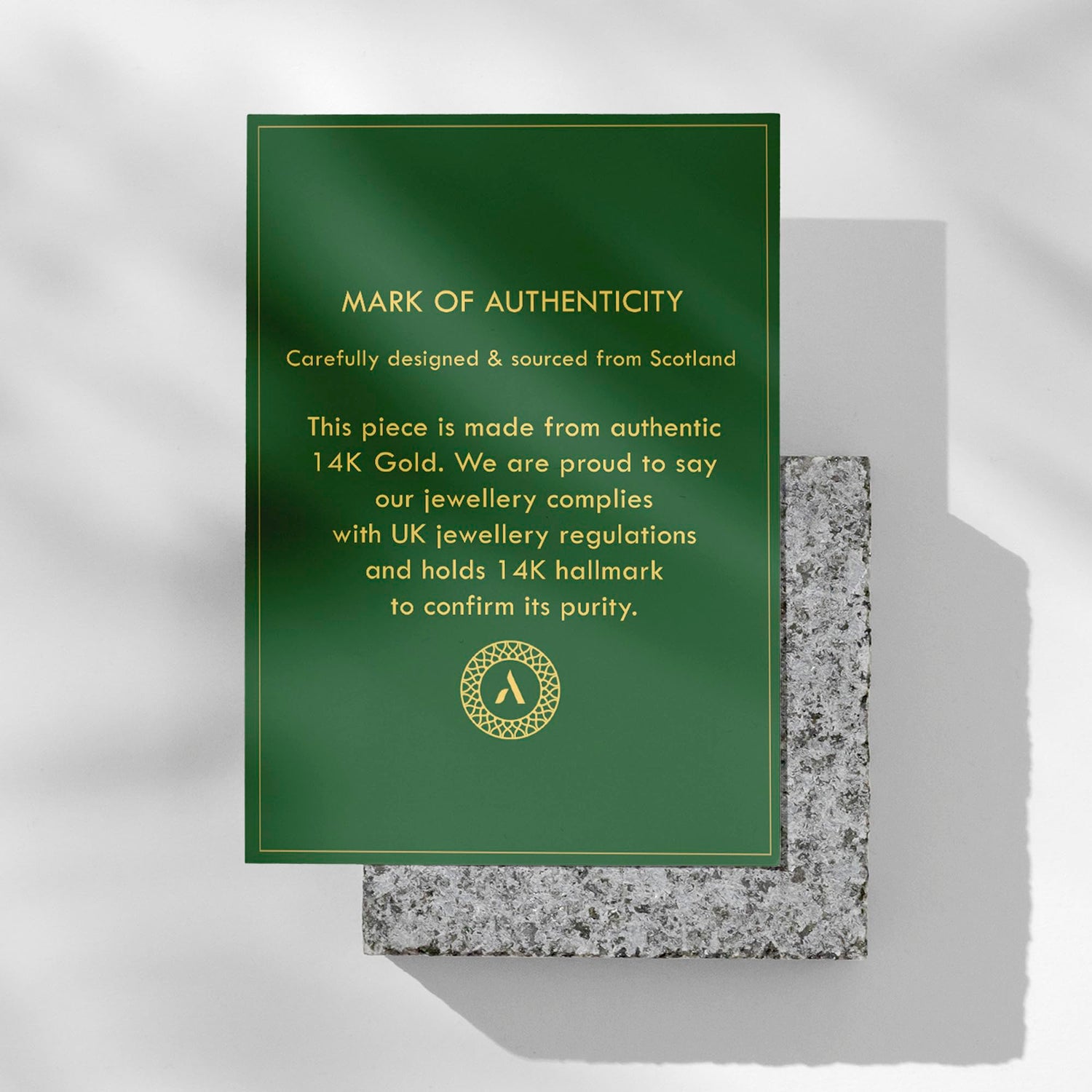 Amberta Solid Italian 14K Yellow Gold Wedding Band with authenticity card on stone background