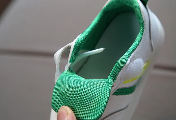 Close-up of white sneaker with green mesh accents, perforated side, and low-top fit