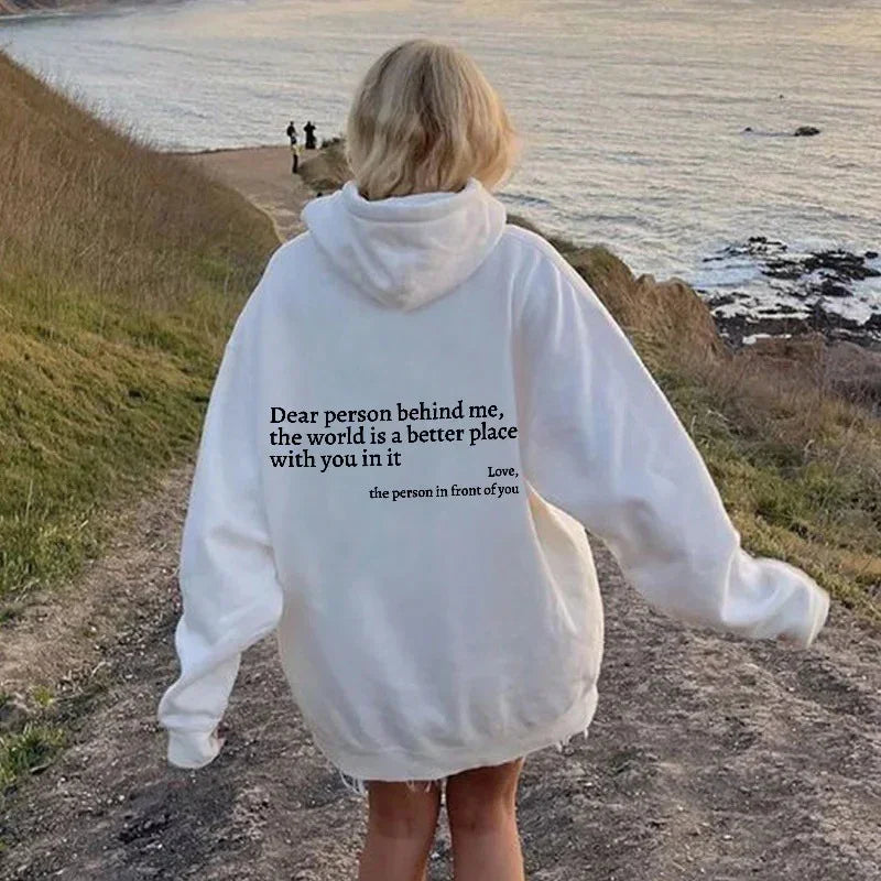 Oversized white hoodie with inspirational back text, relaxed streetwear fit, outdoor setting