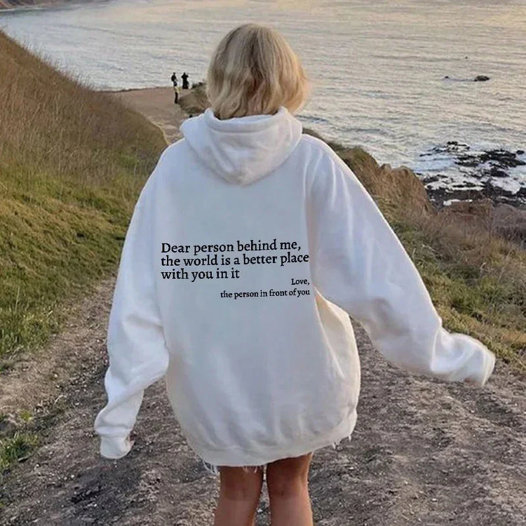 Oversized white hoodie with inspirational back text, relaxed streetwear fit, outdoor setting