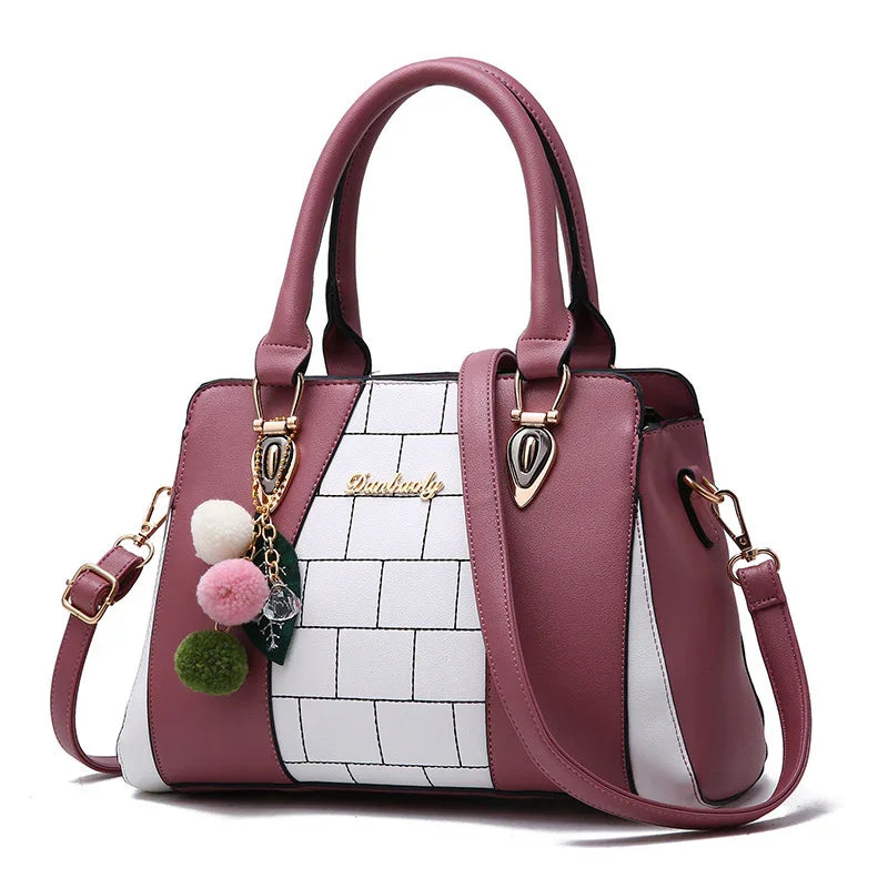 Pink and white colorblock handbag with faux leather finish, gold hardware, and pom pom charm