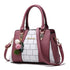 Pink and white colorblock handbag with faux leather finish, gold hardware, and pom pom charm