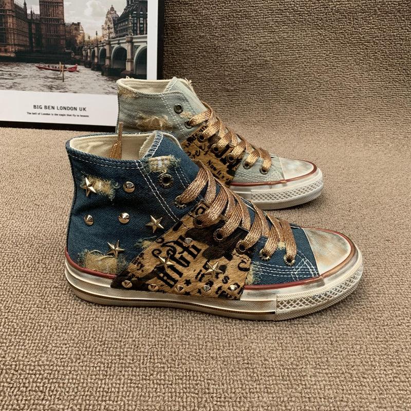 High top denim sneakers with distressed details, bronze studs, graffiti print, and gold laces