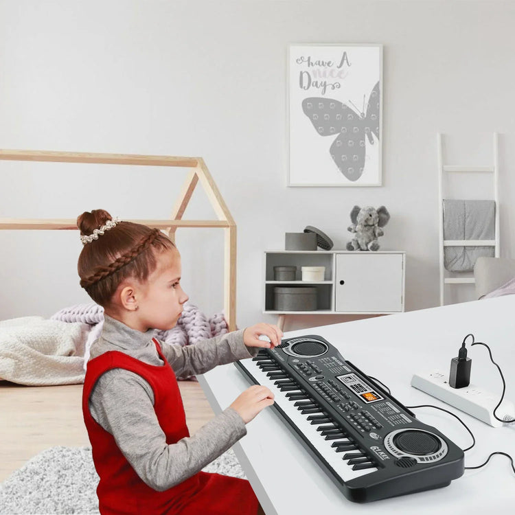 Girl in red sleeveless dress over gray turtleneck playing keyboard piano in modern room